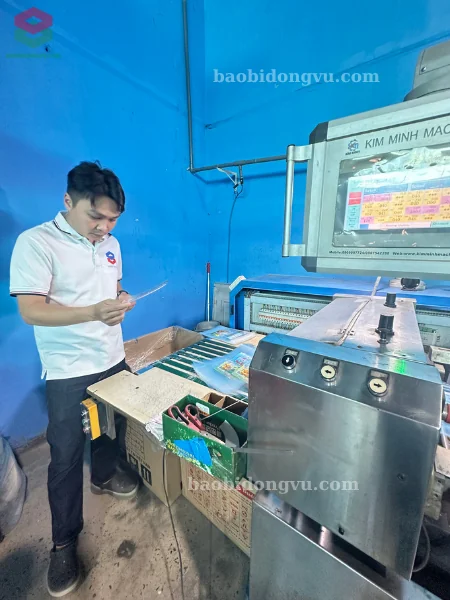 Kĩ thuật viên kiểm tra kĩ sản phẩm bao bì trong khi máy đang cắt bao bì